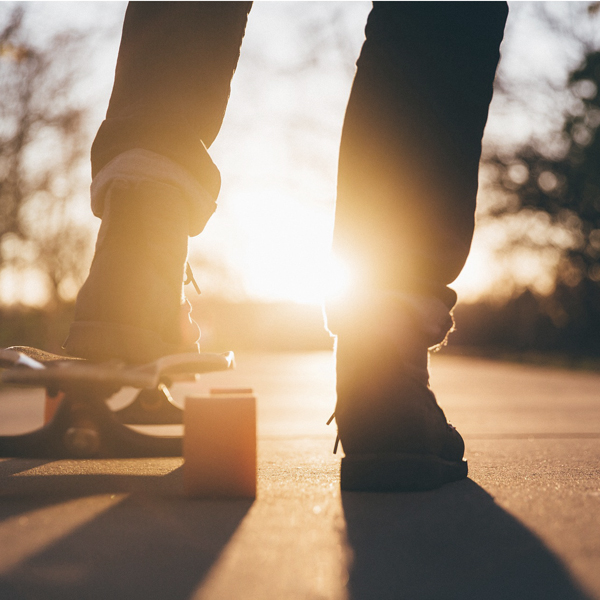 fötter på skateboard i motljus